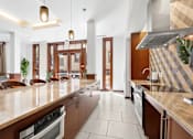 Thumbnail 12 of 32 - A modern kitchen with brown cabinets and a marble countertop.