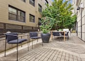 Thumbnail 23 of 32 - A patio with a table and chairs surrounded by buildings.