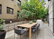 Thumbnail 24 of 32 - A patio with a table and chairs surrounded by buildings.