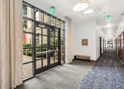 Thumbnail 26 of 32 - A hallway with a blue carpet and a glass door leading outside.