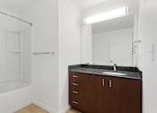 Thumbnail 7 of 32 - A bathroom with a sink, mirror, and bathtub.