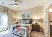 Thumbnail 14 of 31 - A bedroom with a bed, a chair, and a ceiling fan.
