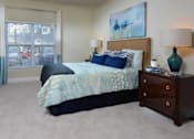 Thumbnail 15 of 31 - A bedroom with a bed, nightstand, and a painting on the wall.