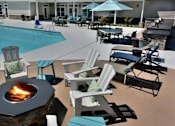 Thumbnail 16 of 31 - A fire pit sits in the middle of a patio with chairs around it.