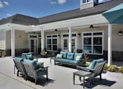 Thumbnail 19 of 31 - A patio with a couch, chairs, and a table.