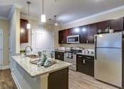 Thumbnail 1 of 31 - A kitchen with a granite countertop and stainless steel appliances.