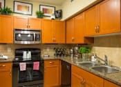 Thumbnail 12 of 16 - A kitchen with brown cabinets and a black oven.