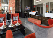 Thumbnail 8 of 16 - A modern living room with orange chairs and a black table.