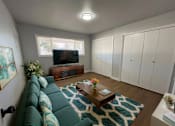 Thumbnail 3 of 21 - A living room with a green couch and a wooden coffee table.