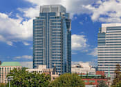 Thumbnail 75 of 78 - A tall building with a glass facade stands in front of a sky with clouds.