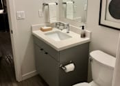 Thumbnail 12 of 24 - A bathroom with a toilet, sink, and mirror.