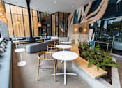 Thumbnail 27 of 40 - a seating area with tables and chairs in a hotel lobby at Brookland Apartments, Portland, 97202