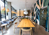 Thumbnail 22 of 40 - A long wooden table is surrounded by chairs in a room with a wall mural at Brookland Apartments, Portland