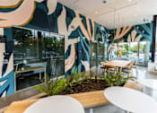 Thumbnail 2 of 40 - a communal area with tables and chairs and a large mural on the wall at Brookland Apartments, Portland, Oregon