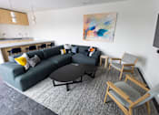 Thumbnail 3 of 40 - A grey couch with a yellow pillow is in the middle of a grey rug in a living room at Brookland Apartments, Oregon
