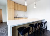 Thumbnail 36 of 40 - a kitchen with a white counter top and black bar stools at Brookland Apartments, Oregon