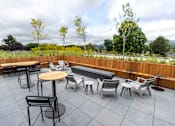 Thumbnail 25 of 40 - a rooftop patio with tables and chairs and a pool at Brookland Apartments, Portland, OR 97202