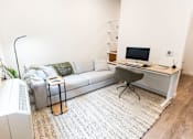 Thumbnail 21 of 40 - a living room with a couch and a desk with a computer at Brookland Apartments, Portland, Oregon