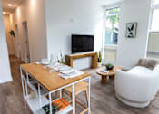 Thumbnail 19 of 40 - a living room with a table and a couch and a television at Brookland Apartments, Portland, OR