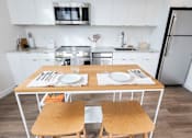 Thumbnail 33 of 40 - a kitchen with white cabinets and a wooden table with two chairs at Brookland Apartments, Portland, 97202