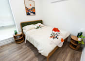 Thumbnail 17 of 40 - a bedroom with a bed with a white comforter and pillows at Brookland Apartments, Oregon 97202