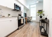 Thumbnail 15 of 40 - A modern kitchen with a white cabinet and a black stove top oven at Brookland Apartments, Portland