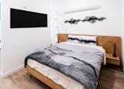 Thumbnail 37 of 40 - a bedroom with white walls and a bed with a gray blanket at Brookland Apartments, Oregon 97202