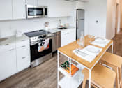 Thumbnail 39 of 40 - a kitchen with white cabinets and a wooden table at Brookland Apartments, Portland, OR