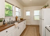Thumbnail 6 of 13 - A kitchen with white cabinets and a white fridge.