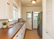Thumbnail 5 of 13 - A kitchen with white cabinets and a brown countertop.