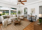 Thumbnail 1 of 13 - A living room with a white couch, a wooden coffee table, and a ceiling fan.