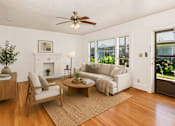 Thumbnail 3 of 13 - A living room with a fireplace, a sofa, a chair, a coffee table, and a potted plant.