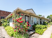 Thumbnail 9 of 13 - A house with a flower bed in front of it.