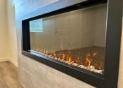 Thumbnail 11 of 46 - Large glass fireplace in a room with wood floors at Thrive at Green Mountain, Camas
