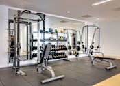 Thumbnail 8 of 78 - A gym with a variety of equipment including a squat rack, bench, and weights.