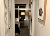 Thumbnail 11 of 24 - A hallway with a bedroom at the end.