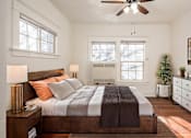 Thumbnail 25 of 28 - A bedroom with a bed, nightstand, and a ceiling fan.