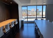 Thumbnail 24 of 78 - A conference room with a long table and chairs facing a window with a view of a cityscape.