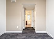 Thumbnail 28 of 78 - A hallway with a carpeted floor and a doorway leading to a bathroom.