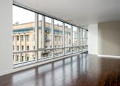 Thumbnail 62 of 78 - A room with a large window overlooking a street with buildings.