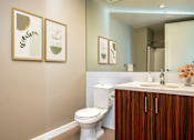 Thumbnail 71 of 78 - A bathroom with a toilet, sink, and framed pictures on the wall.