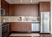 Thumbnail 70 of 78 - A modern kitchen with wooden cabinets and stainless steel appliances.