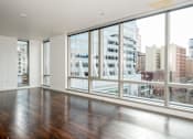 Thumbnail 61 of 78 - A large empty room with wooden floors and large windows overlooking a cityscape.