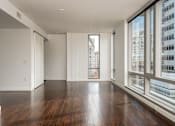 Thumbnail 59 of 78 - A large empty room with wooden floors and a view of a cityscape through the windows.