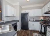 Thumbnail 25 of 31 - a kitchen with white cabinets and a black refrigerator at Carrington Place at Wildewood, Columbia  