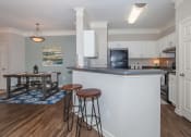 Thumbnail 27 of 31 - a kitchen with a counter top bar and stools at Carrington Place at Wildewood, Columbia, SC 29223  