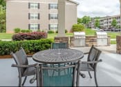Thumbnail 2 of 17 - a patio with a table and chairs in front of an apartment complex at The Bristol Apartments, Greenville, SC