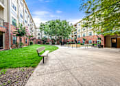 Thumbnail 2 of 25 - A bench is situated on a concrete area in front of a building.