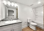 Thumbnail 12 of 25 - A white toilet sits in a bathroom next to a sink and a mirror.