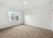 Thumbnail 15 of 25 - A large empty room with a carpeted floor and a window.
